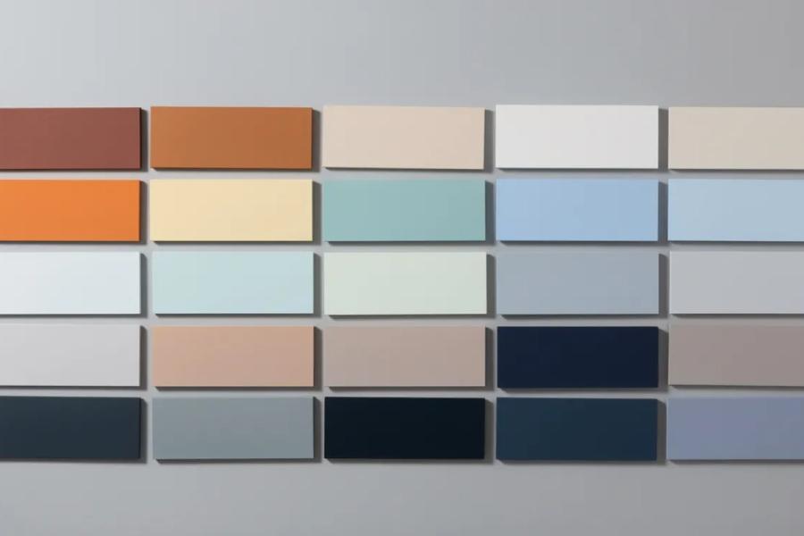 Cuadrícula de muestras de color rectangulares sobre una pared gris, desde el terracota y el naranja hasta azules suaves, tonos neutros y azul marino