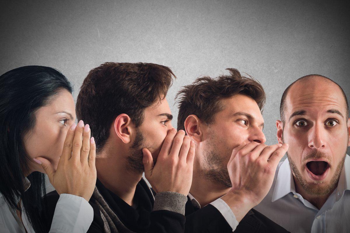 Four people participating in a whispering game, with each person passing a message to the next, ending with a surprised reaction from the last person.